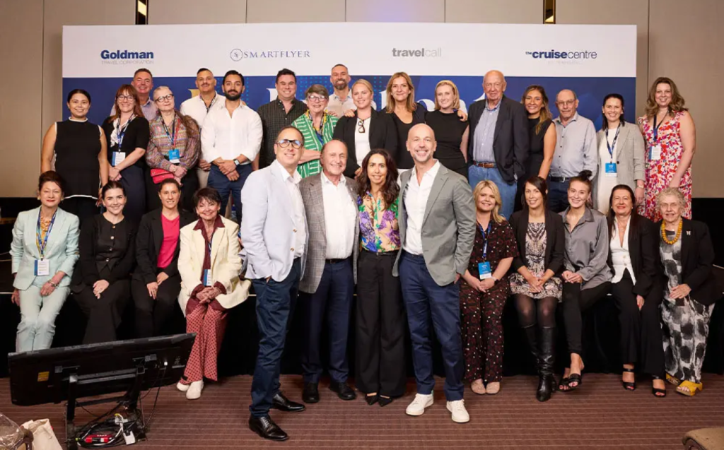 Goldman Group team photo in front of media wall