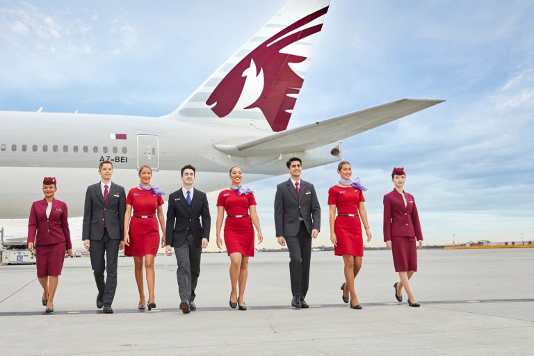 Uniformed Virgin Australia and Qatar Airways crew walk in front of a Qatar aircraft.